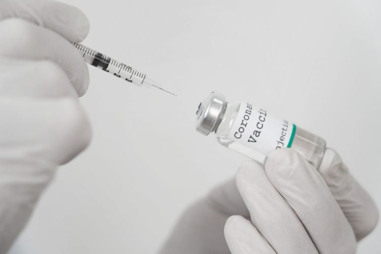 medic with latex gloves holding vaccine