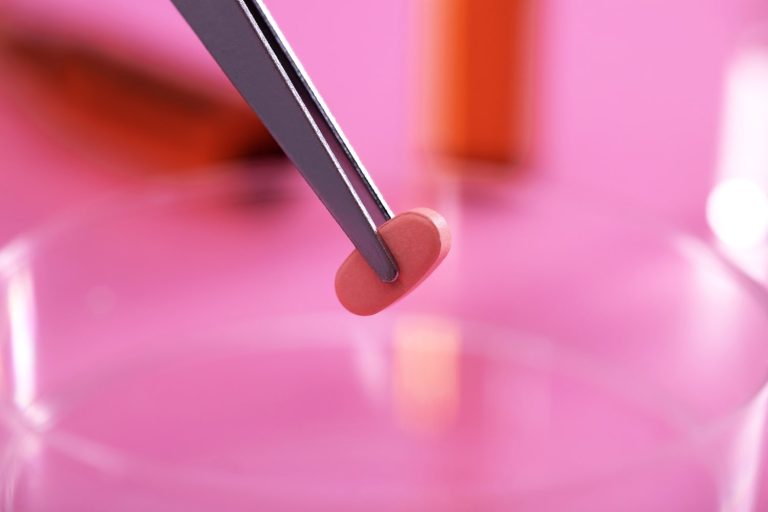 selective focus shot gray tweezers holding small pill lab