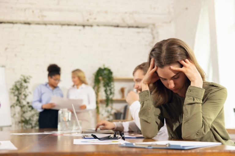 stressed out girl in office while her colleagues using-devices gadgets during creative meeting